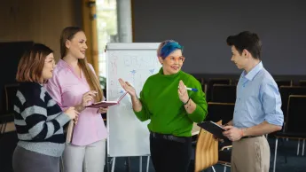Projektowanie Ekologiczne i Architektura Zieleni (Eco Design) | Uniwersytet WSB Merito Bydgoszcz: grupa studentów stoi i dyskutuje przy tablicy typu flipchart