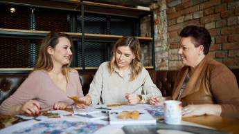 Terapia pedagogiczna | Studia I stopnia w Bydgoszczy | Uniwersytet WSB Merito Bydgoszcz: troje studentem w różnym wieku pracuje nad wspólnym projektem przy stole