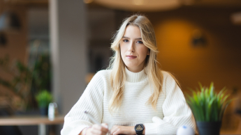 Zarządzanie projektami | Studia I stopnia w Bydgoszczy | Uniwersytet WSB Merito Bydgoszcz: Studentka WSB Merito Bydgoszcz siedzi przy stole robiąc notatki w przytulnym pomieszczniu