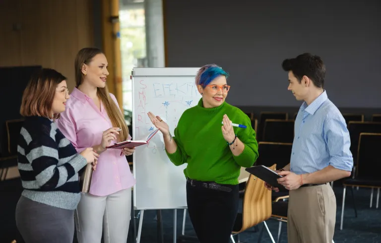 Nasze wartości | Uniwersytet WSB Merito Bydgoszcz: grupa studentów stoi i dyskutuje przy tablicy typu flipchart