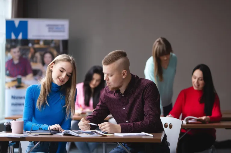 ABC studenta | Uniwersytet WSB Merito Bydgoszcz: dwóch studentów w sali wykładowej przy biurku z książkami