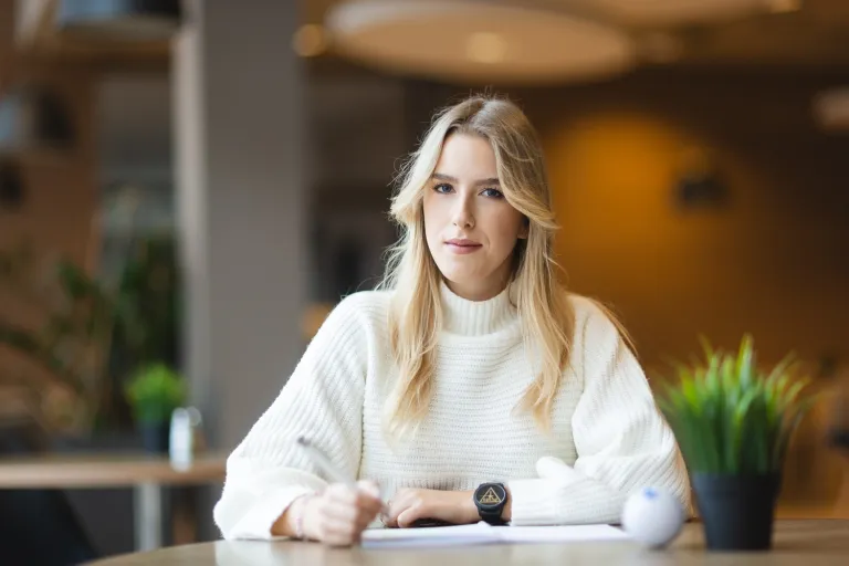 Zarządzanie w branży kosmetycznej i dietetycznej | Studia II stopnia w Bydgoszczy | Uniwersytet WSB Merito Bydgoszcz: Studentka WSB Merito Bydgoszcz siedzi przy stole robiąc notatki w przytulnym pomieszczniu