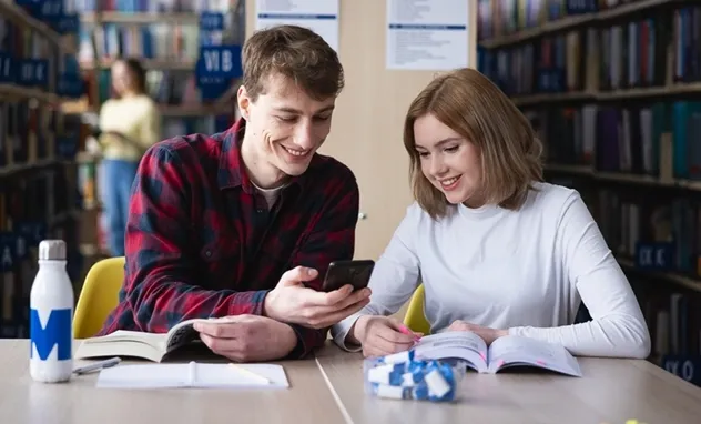 41. Czwartki Social Media 16 kwietnia! | Aktualności | Uniwersytet WSB Merito Bydgoszcz: student pokazuje studentce ciekawą rzecz w telefonie