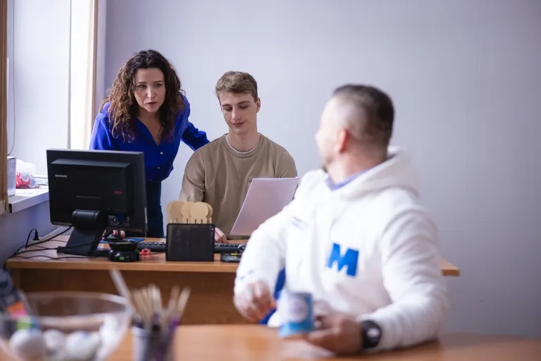 Seminarium PMI na UWSB Merito Bydgoszcz | 28.05.2026 | Aktualności | Uniwersytet WSB Merito Bydgoszcz: student odwrócony w kierunku dwójki studentów siedzących przy komputerze