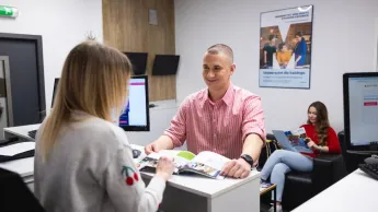 Psychologia komunikacji | Studia jednolite magisterskie w Chorzowie | Uniwersytet WSB Merito Chorzów: student rozmawiający z pracownikiem działu rekrutacji