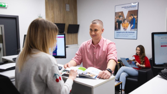 Turystyka i rekreacja | Studia I stopnia w Chorzowie | Uniwersytet WSB Merito Chorzów: student rozmawiający z pracownikiem działu rekrutacji