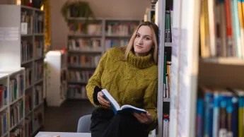 Pracownik Działu Prawnego | Studia II stopnia w Chorzowie | Uniwersytet WSB Merito Chorzów: studentka przeglądająca książki w bibliotece 