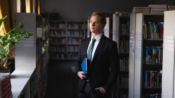 Zarządzanie finansami w biznesie | Studia II stopnia ze studiami podyplomowymi  | Uniwersytet WSB Merito Chorzów: Student stojący w bibliotece