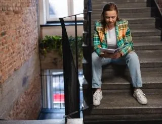 Inżynieria wirtualna i sztuczna inteligencja | Studia I stopnia w Chorzowie | Uniwersytet WSB Merito Chorzów: studentka czytająca notatki na schodach
