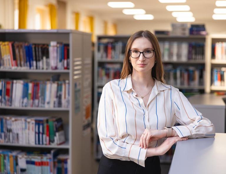 Stypendia i zniżki | Uniwersytet WSB Merito Chorzów: Studentka stojąca w bibliotece