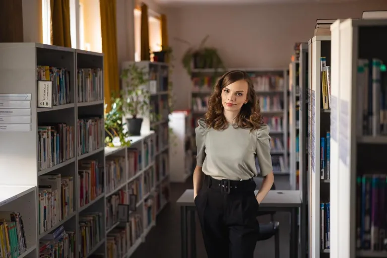 Maturzyści | Uniwersytet WSB Merito Chorzów: studentka stojąca w bibliotece 