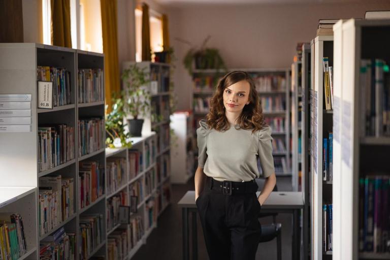 Maturzyści | Uniwersytet WSB Merito Chorzów: studentka stojąca w bibliotece 