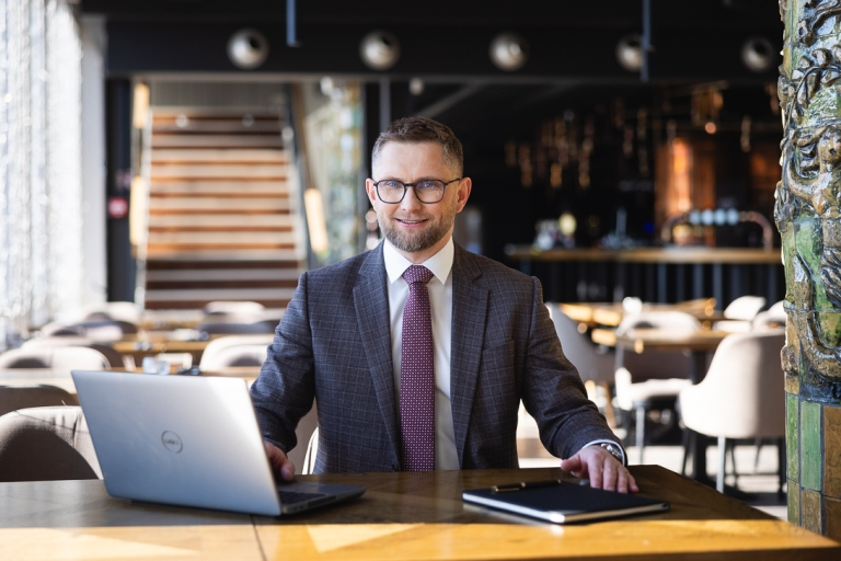 Studia MBA w Chorzowie | Uniwersytet WSB Merito Chorzów: Uczestnik studiów MBA pracuje przy stole z laptopem i notesem- Uniwersytet WSB Merito Chorzów