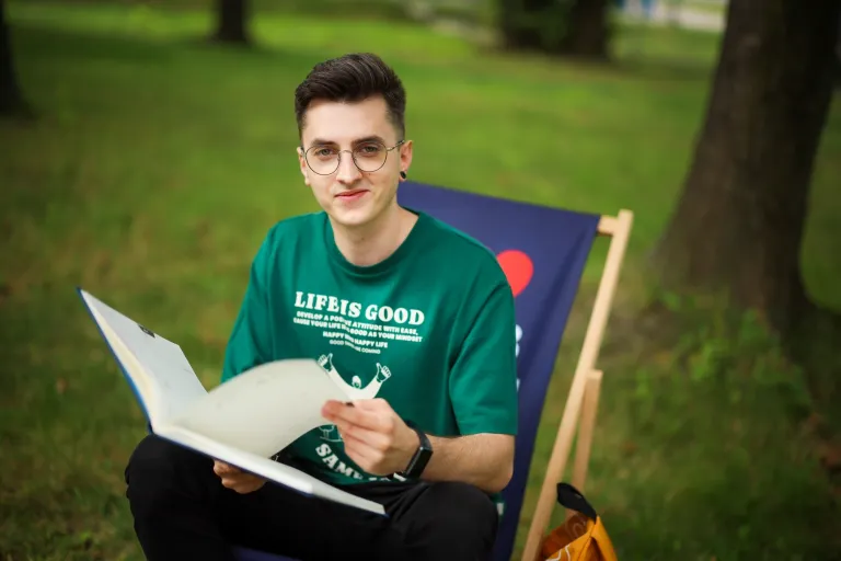 Wyniki wyszukiwania | Uniwersytet WSB Merito Chorzów: Student WSB MErito siedzi na leżaku w parku i przegląda notatnik