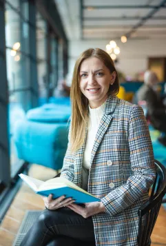 Who we are | WSB Merito Bydgoszcz University: studentka z książką w dłoniach siedzi na krześle