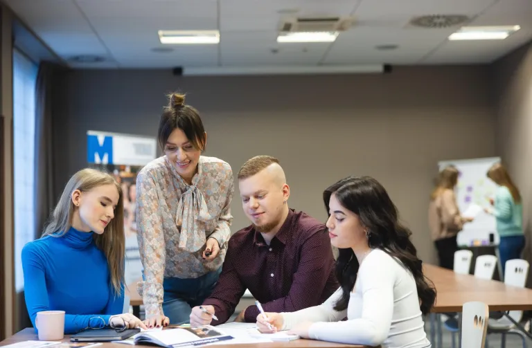 Master's degree | WSB Merito Bydgoszcz University: troje studentów i wykładowczyni pracują nad projektem przy stole