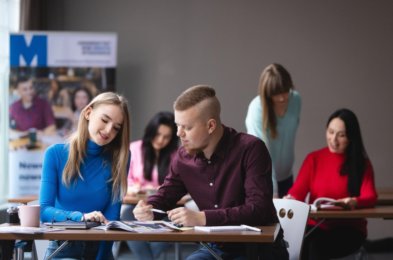 Student ABC | WSB Merito Bydgoszcz University: dwóch studentów w sali wykładowej przy biurku z książkami
