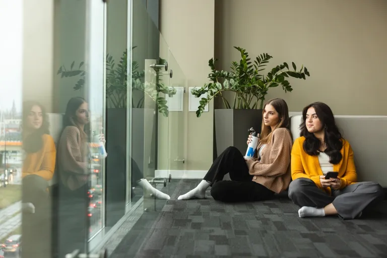 Our values | WSB Merito Bydgoszcz University: Grafika główna: praktyczność i przyjazność WSB Merito Bydgoszcz - dwie dziewczyny siedzą na podłodze w strefie studenta