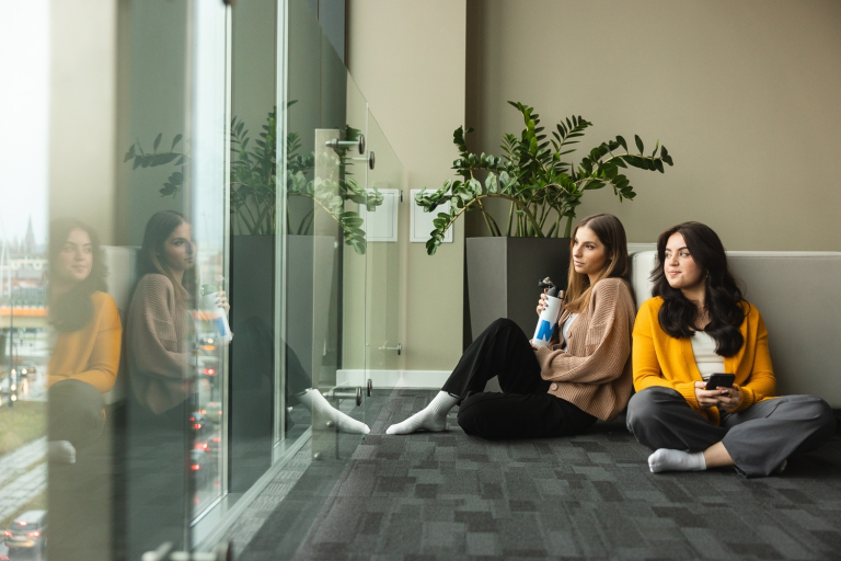 Our values | WSB Merito Bydgoszcz University: Grafika główna: praktyczność i przyjazność WSB Merito Bydgoszcz - dwie dziewczyny siedzą na podłodze w strefie studenta