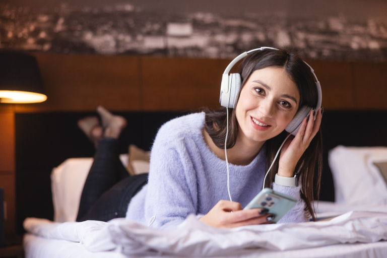 Our values | WSB Merito Bydgoszcz University: Dziewczyna leży na łóżku i słucha muzyki przez słuchawki