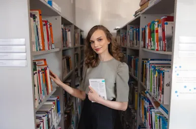 Library | WSB Merito University in Chorzów: studentka przegląda książki w bibliotece