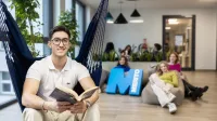 Management | WSB Merito Gdańsk University: Student siedzi w hamaku i w rękach trzyma książkę, a za nim siedzą studentki
