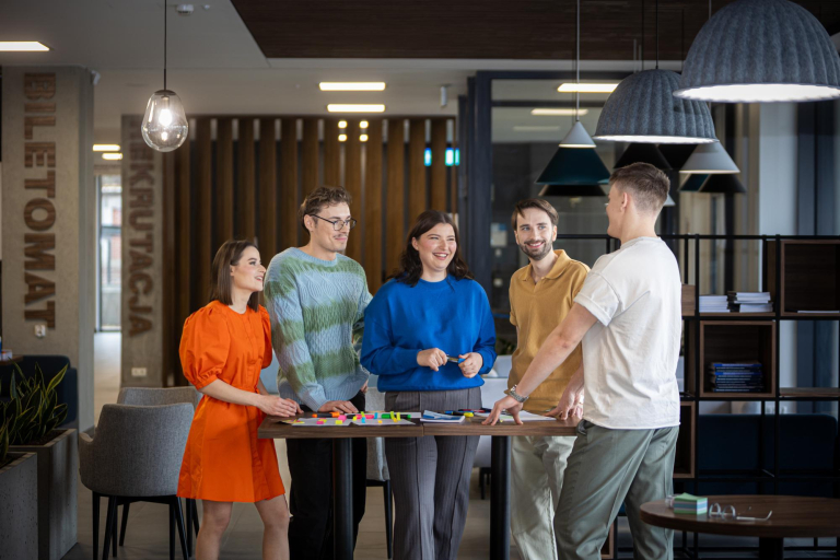 Search results | WSB Merito Gdańsk University: Studenci stojący przy stole w holu, dyskutują warsztatowo