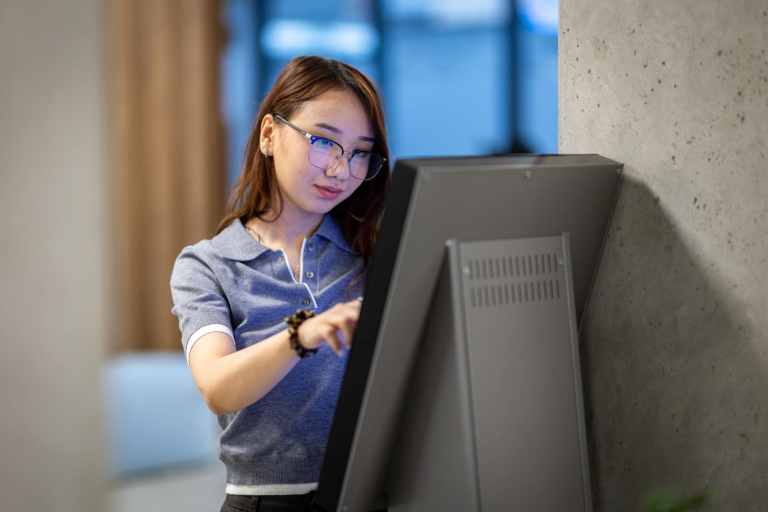 University without barriers | WSB Merito Gdańsk University: Dziewczyna korzysta z ekranu dotykowego. Ma na sobie okulary i jest azjatyckiej urody