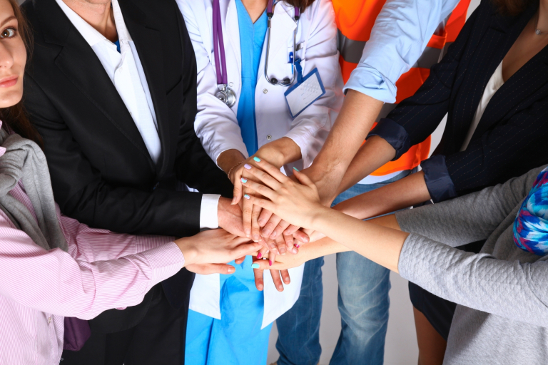 IACBE Accreditation | WSB Merito Gdańsk University: Ludzie w geście solidarności, jedna z osób ma na sobie fartuch