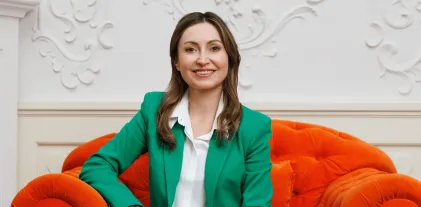 University authorities | WSB Merito Gdańsk University: Zdjęcie uśmiechniętej kobiety w zielonej marynarce na pomarańczowym fotelu