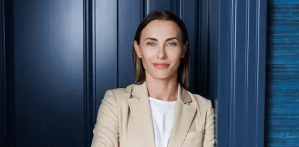 University authorities | WSB Merito Gdańsk University: Młoda i uśmiechnięta kobieta w beżowej marynarce w tle turkusowych ścian