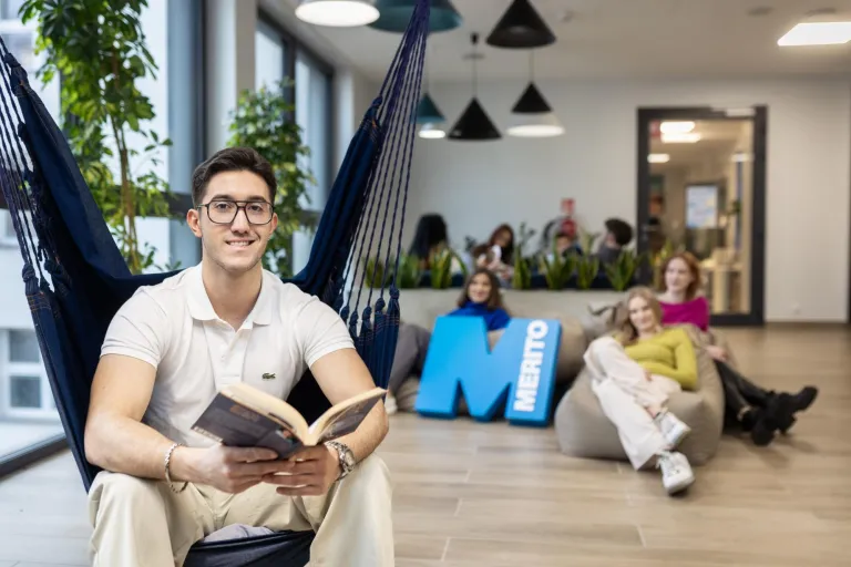 International Business - BA Business and Management Top-Up with University of Northampton, studia I stopnia, licencjackie i inżynierskie: Student siedzi w hamaku i w rękach trzyma książkę, a za nim siedzą studentki