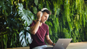 Management | WSB Merito Łódź University: Młody mężczyzna w słuchawkach pracuje na laptopie.