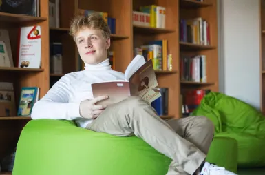 Our campus | WSB Merito Łódź University: Uczeń czyta książkę w bibliotece Uniwersytetu WSB Merito w Łodzi