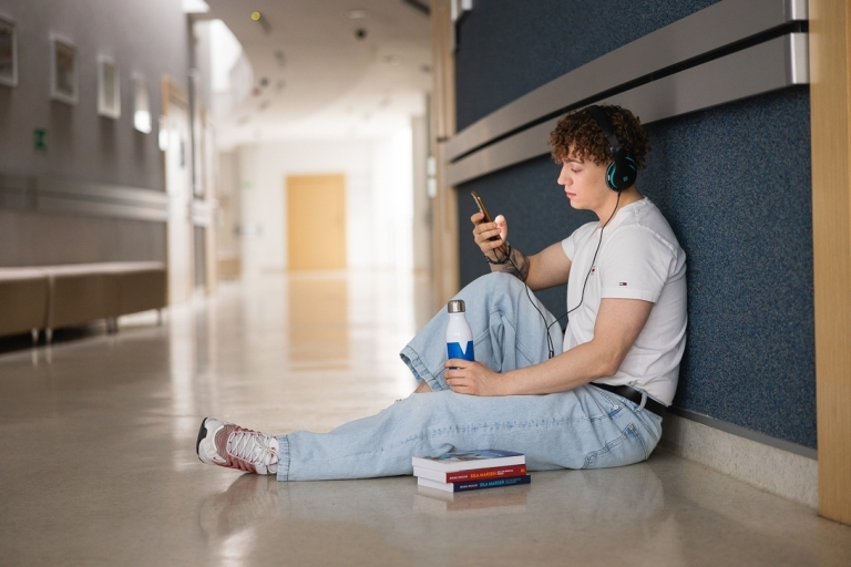 Language certificates | WSB Merito Łódź University: A student sitting on the Uni floor