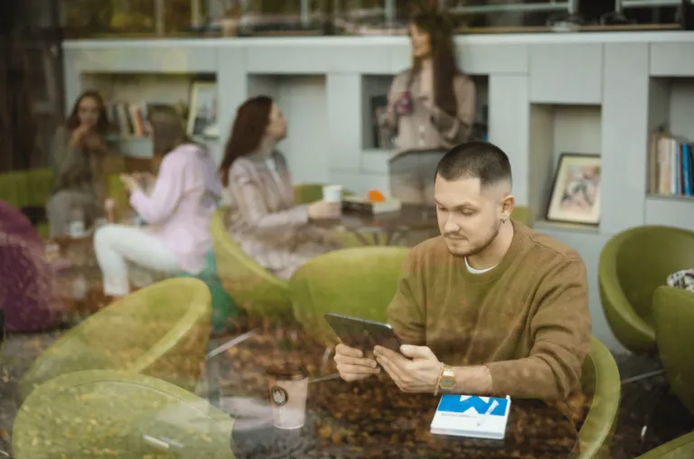 Digital university | WSB Merito Opole University: Student korzystający z tabletu. Siedzi w kawiarni