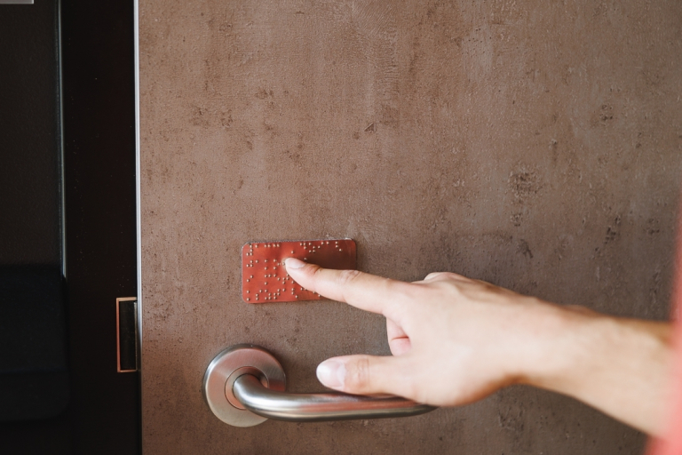 University without barriers | WSB Merito Opole University: Osoba czytająca oznaczenie w alfabecie Braille’a