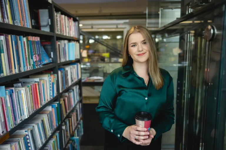 Management | WSB Merito Opole University: Studentka stojąca między regałami w bibliotece