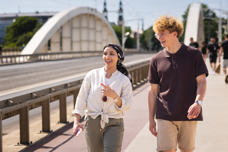 Student Council | WSB Merito Poznań University: Grafika główna: samorząd WSB Merito Poznań - studetnka i student WSB Merito Poznań idą przez most w Poznaniu