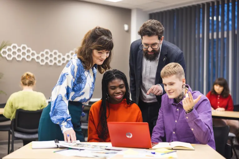Computer Science | WSB Merito Poznań University: studenci oraz wykładowcy pochylają się nad laptopem, rozwiązują zadanie