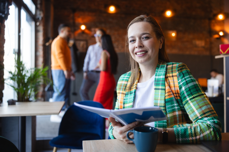 Foreign universities and partners | WSB Merito Universities: Uśmiechnięta dziewczyna zerkająca w obiektyw, trzymająca dokumenty w dłoni