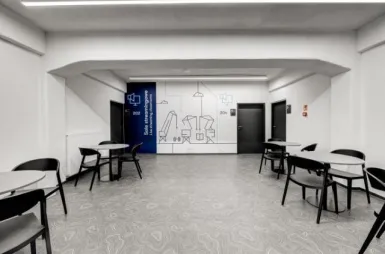 Our campus | Uniwersytet WSB Merito Szczecin: Przestronny korytarz ze stolikami i krzesłami WSB Merito w Szczecinie. 