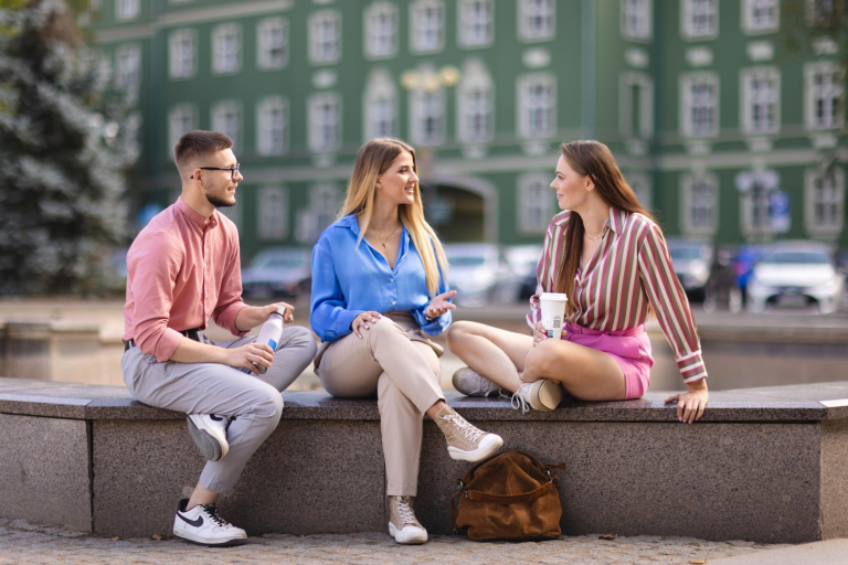 Our values | Uniwersytet WSB Merito Szczecin: Studenci Uniwersytetu WSB Merito rozmawiający na świeżym powietrzu w centrum miasta.
