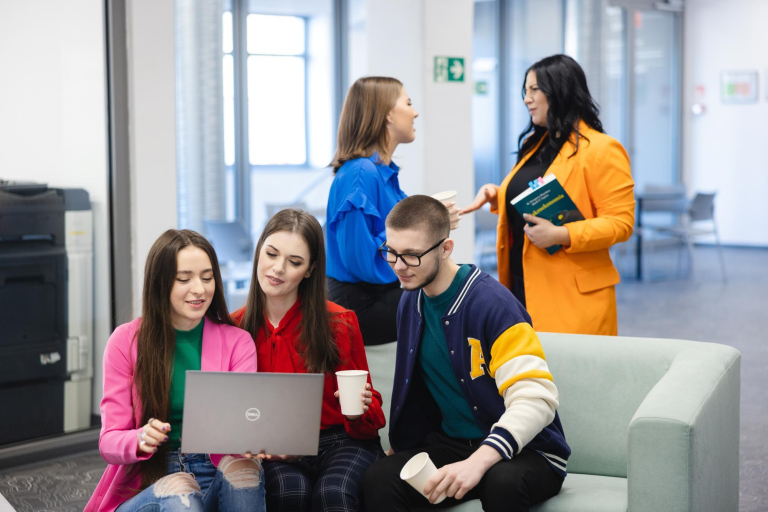 Social impact | Uniwersytet WSB Merito Szczecin: Studenci spędzają czas w strefie relaksu, rozmawiając i pracując na laptopie.