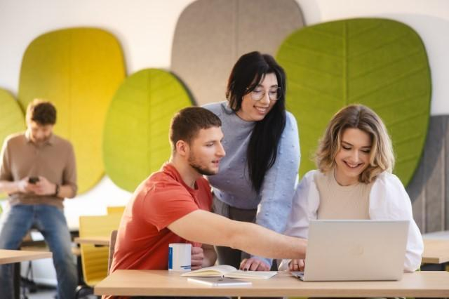 Our campus | Uniwersytet WSB Merito Szczecin: Studenci Uniwersytetu WSB Merito pracujący wspólnie przy laptopie w przestrzeni studenckiej.