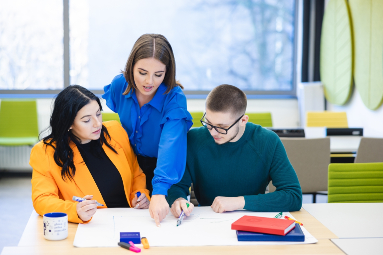 Our values | Uniwersytet WSB Merito Szczecin: Grafika główna: poznaj uczelnię - grupa trzech studentów, dwie dziewczyny i chłopak, na zajęciach warsztatowych na uczelni