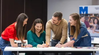 Who we are | WSB Merito Toruń University: grupa uśmiechniętych studentów pracująca nad projektem przy stole