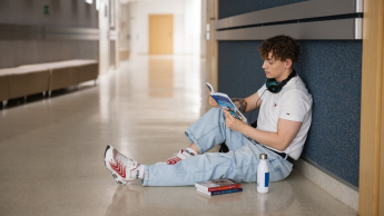 Our campus | WSB Merito Toruń University: Główna grafika: Toruń - studia I stopnia - student siedzący na korytarzu