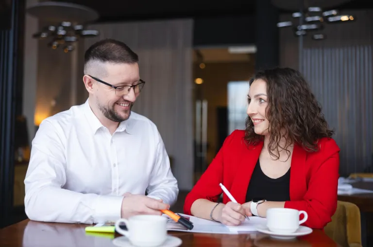 uśmiechnięty mężczyzna i kobieta przy stole dyskutują nad projektem