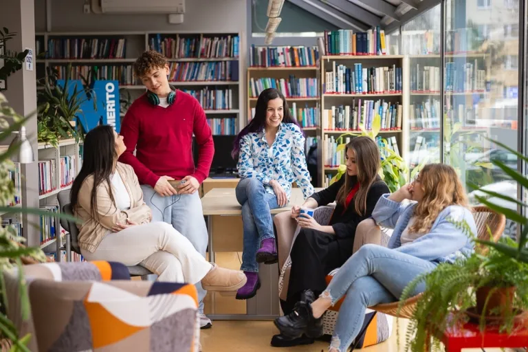University without barriers | WSB Merito Toruń University: Główna grafika: Toruń - studia I stopnia - grupa uśmiechniętych studentów w bibliotece